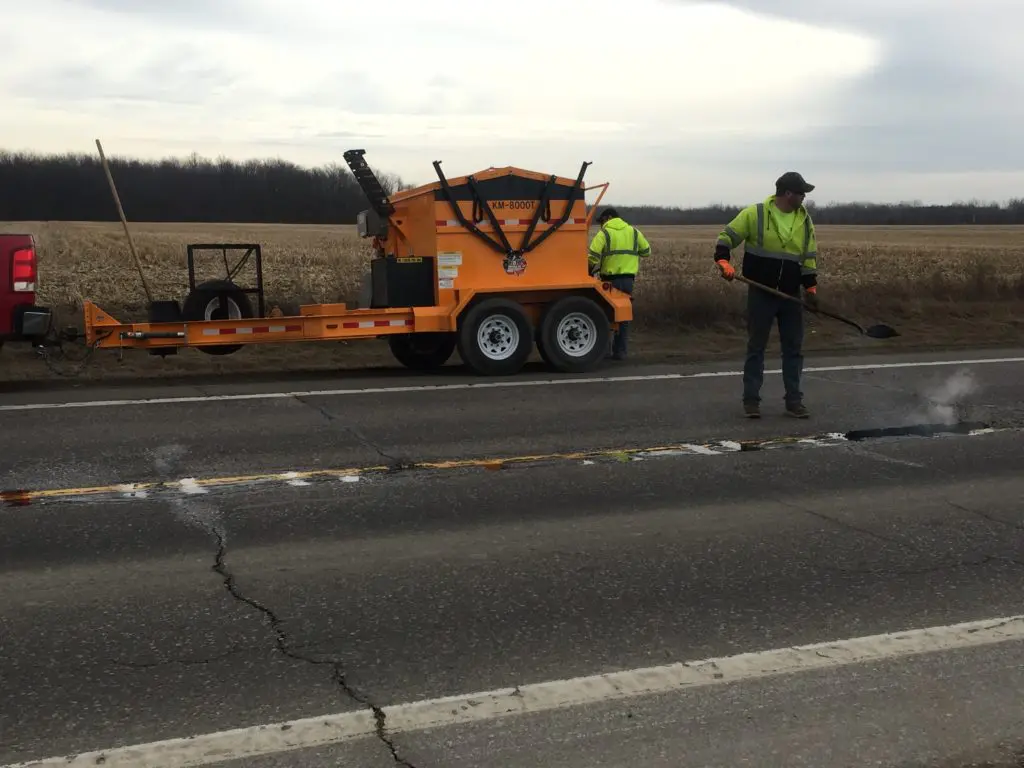 A road maintenance crew patches potholes. 