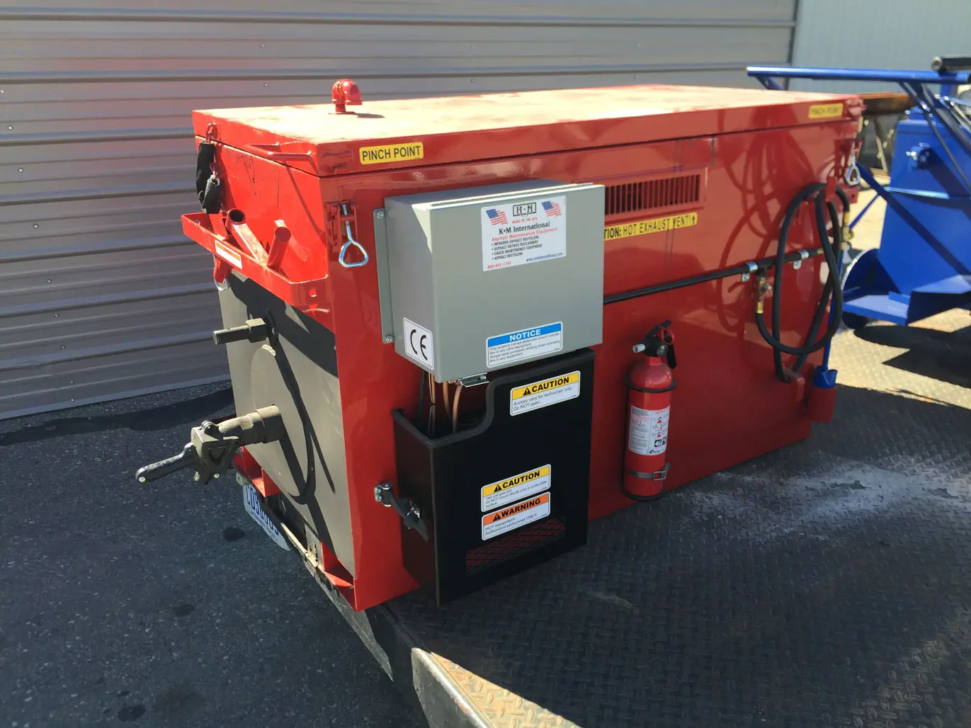 M 55 Rubber Melting Kettle on a job site, highlighting its insulated construction and easy-to-use features like the 2-inch flow valve and agitation paddle for smooth crack filling.