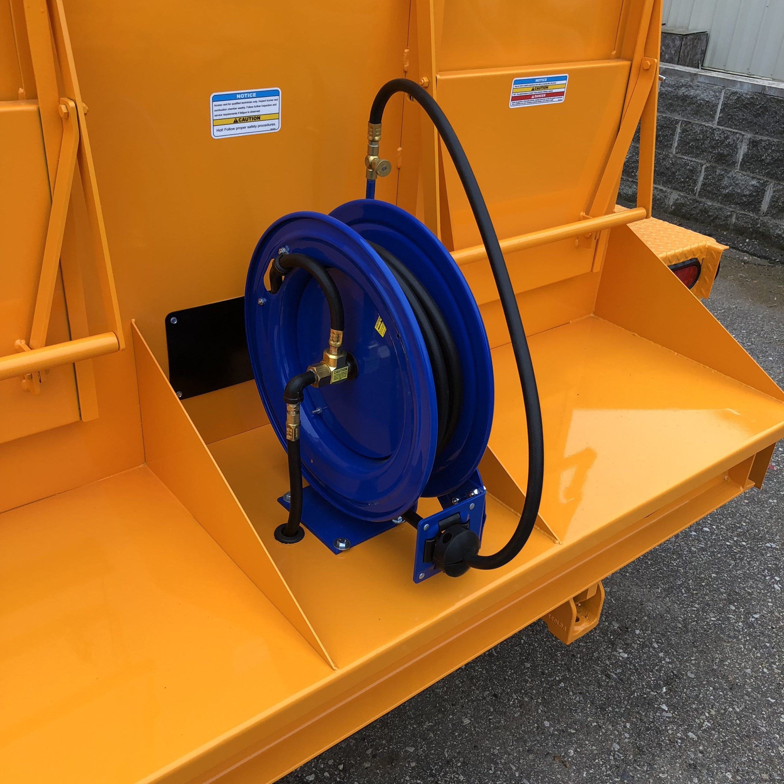 KM International manufactures advanced road repair equipment. A hand torch hose reel is featured in this picture.